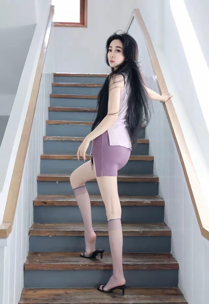 明亮楼梯间，长发女生回眸上楼，穿淡紫无袖上衣与紫色包臀短裙，配半透淡紫中筒丝袜和黑色细跟拖鞋。