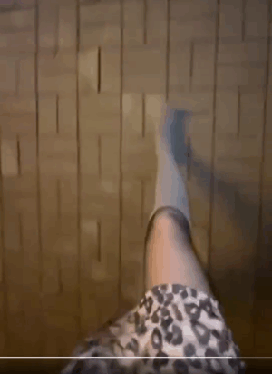 夜晚路灯下的第一视角：穿豹纹半裙、黑色连裤袜与浅色筒靴的女性在木板路上迈步，脚步投下长长影子。