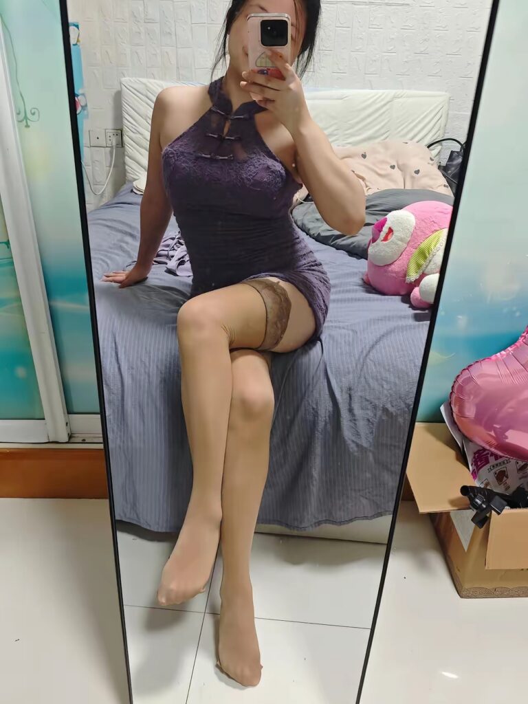 镜前端坐回望，双腿交叠，紫色蕾丝包臀裙与吊带丝袜，脚尖自然点地。