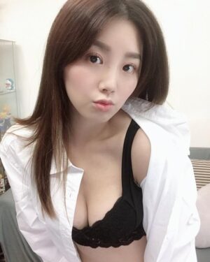 室内自然光下，女生穿白衬衫外搭黑色蕾丝文胸，微嘟嘴看向镜头，妆容清淡，背景为家居陈设，画面干净明亮。