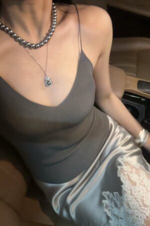 车内座椅上的女孩，灰色针织吊带配银灰缎面裙与珍珠项链。